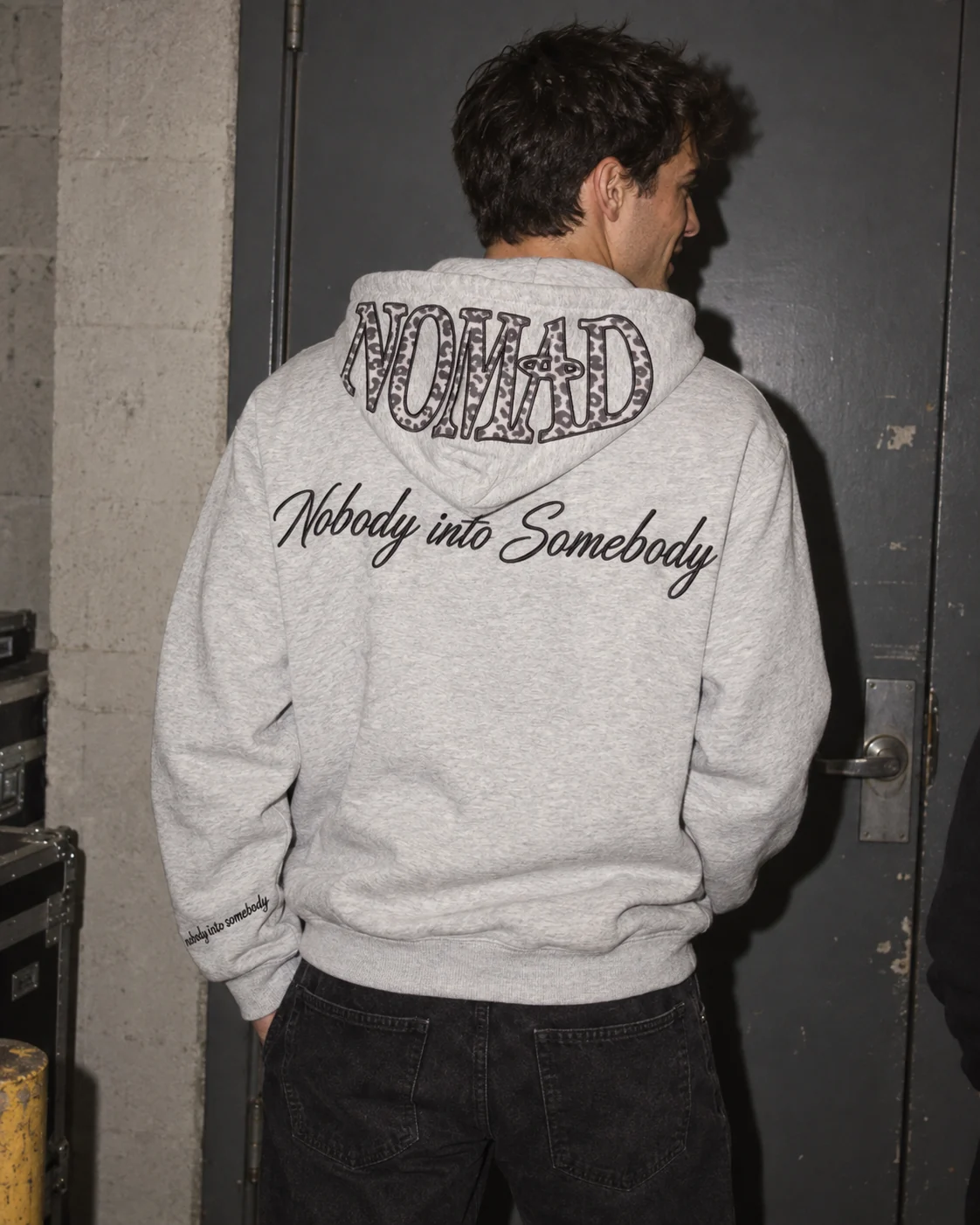 The back of the hoodie worn, NOMAD on the hood and the script across the shoulders.